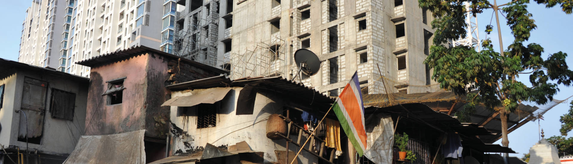 Einfache Behausungen vor Hochhäusern in Mumbai